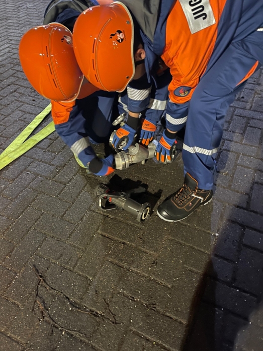 Zwei Jugendliche kuppeln Schläuche während einer Übung auf dem Hof