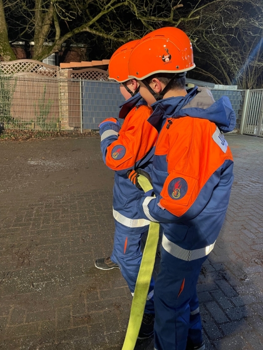 Jugendliche mit Strahlrohr in Bereitschaft, Abendübung am Gerätehaus